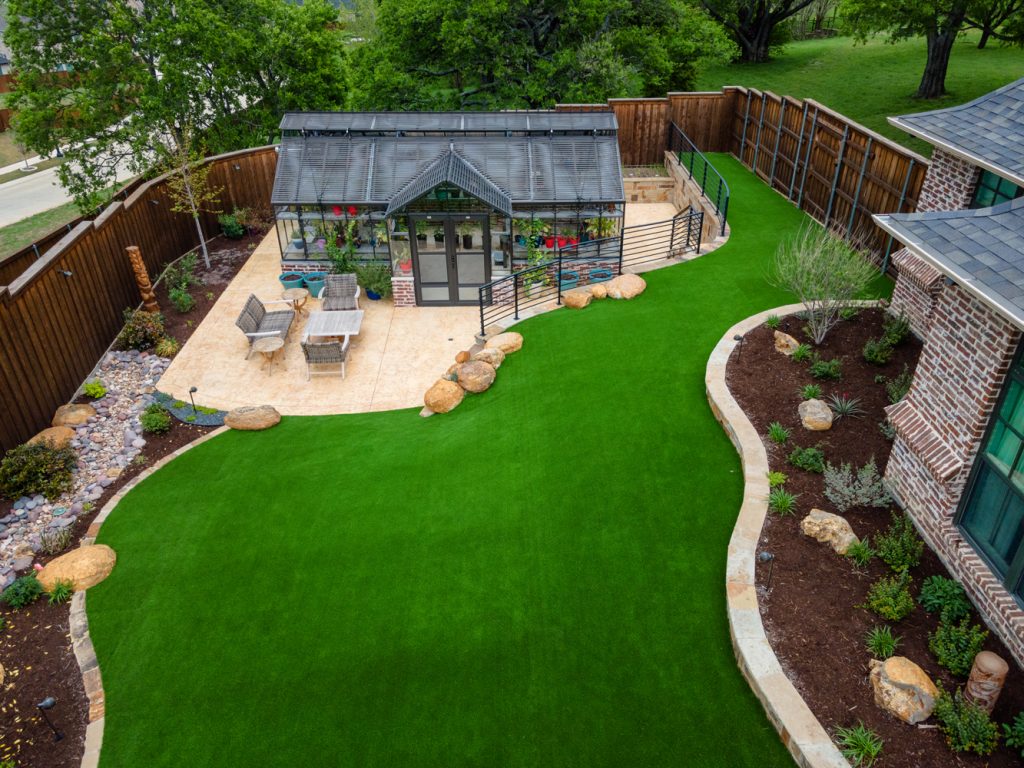 fenced yard with greenhouse and turf grass